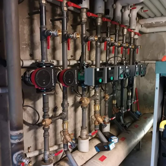 Chaufferie collective avec circulateurs Grundfos et vannes rouges alignées