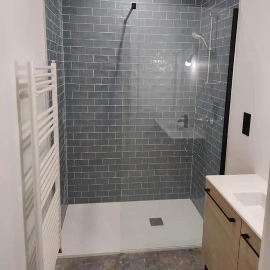 Douche à l’italienne avec faïence bleue, paroi vitrée et sèche-serviettes blanc