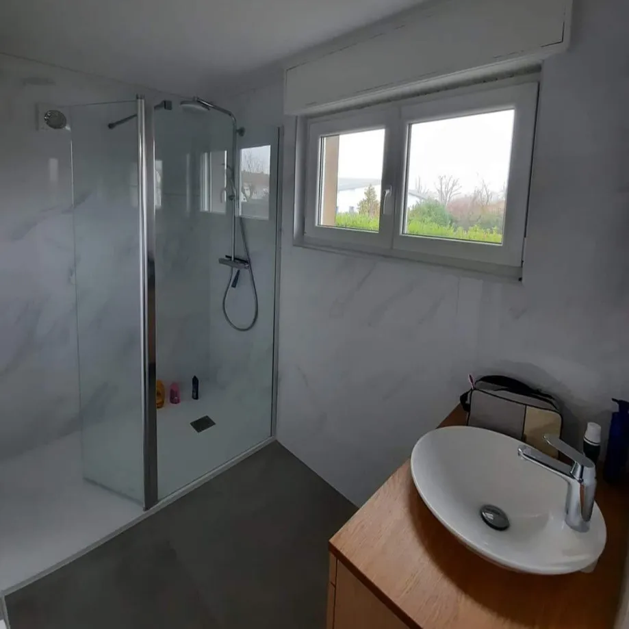 Salle d’eau rénovée avec vasque à poser sur meuble bois et douche d’angle